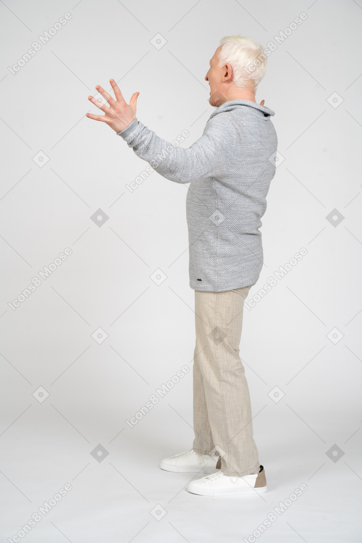 Вид сбоку на мужчину, стоящего и поднимающего руку с растопыренными пальцами