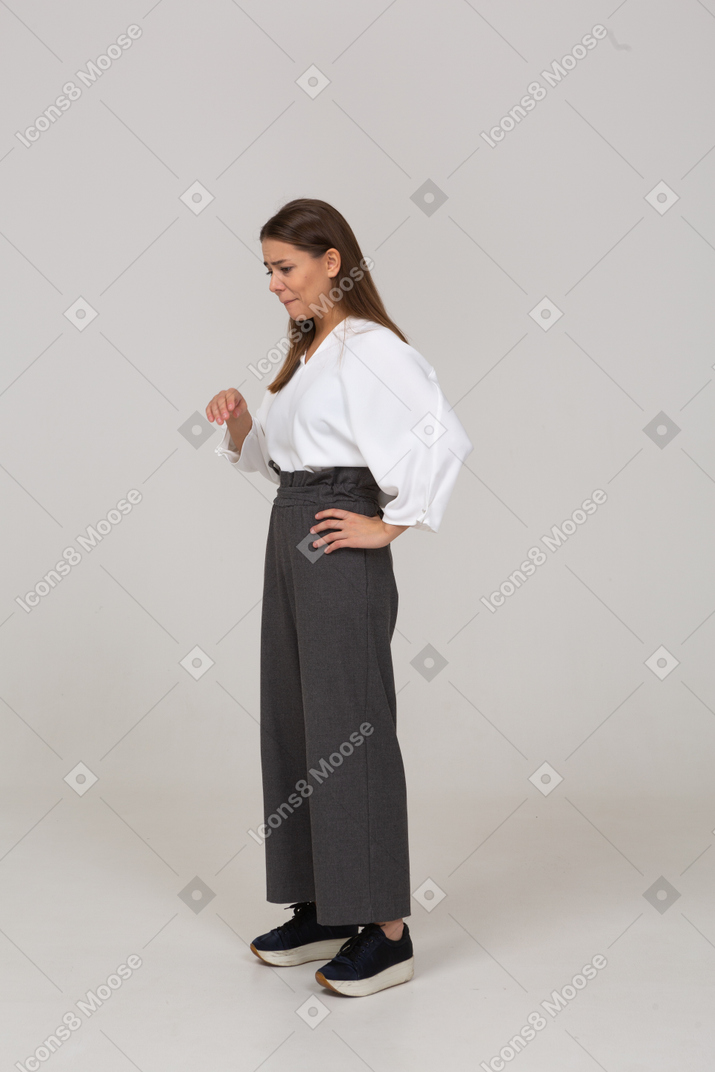 Вид в три четверти грустной молодой леди в офисной одежде, поднимающей руку