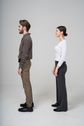 Vista lateral de una joven pareja complacida en ropa de oficina