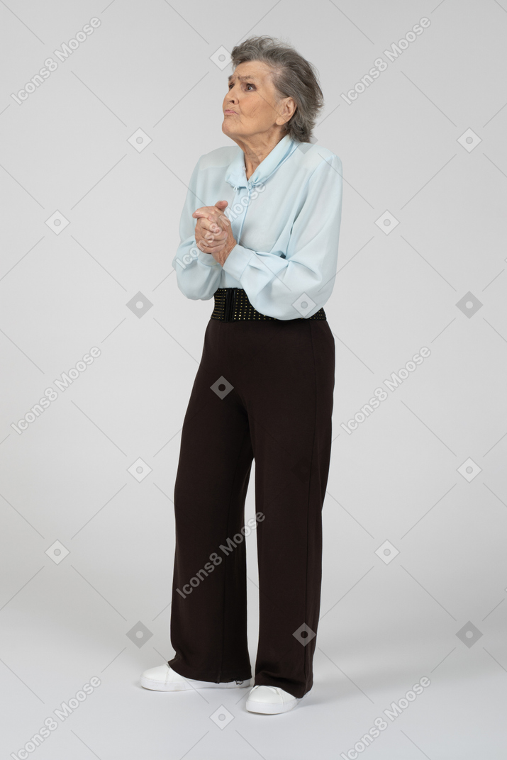 Vista frontale di una donna anziana che sembra ansiosa con le mani giunte