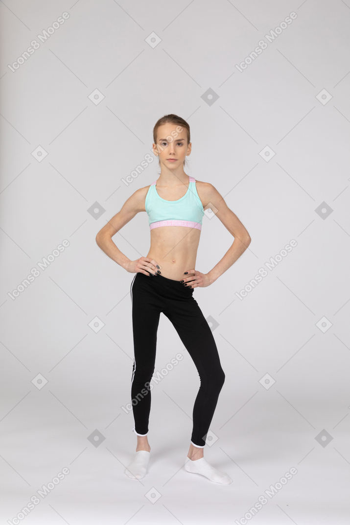 Front view of a teen girl in sportswear putting hands on hips