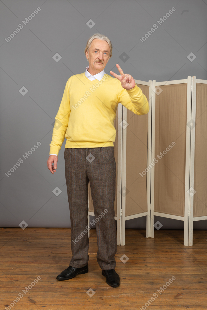 Vue de face d'un vieil homme montrant le signe de la paix
