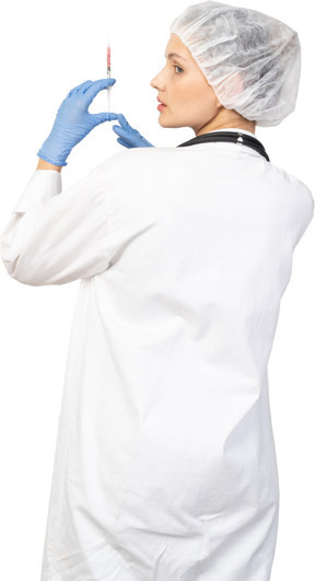 Vista posterior de una joven doctora sosteniendo una jeringa
