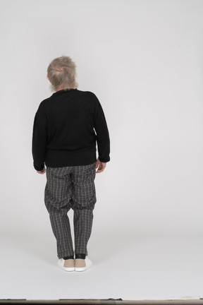 Back view of an elderly man standing with his knees bent