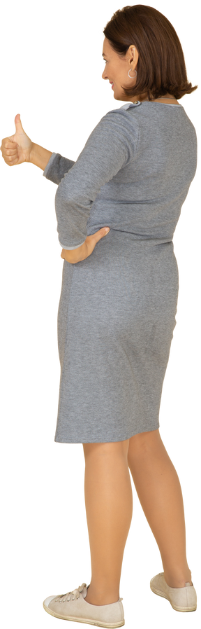 親指を上に表示している灰色のドレスを着た女性の背面図