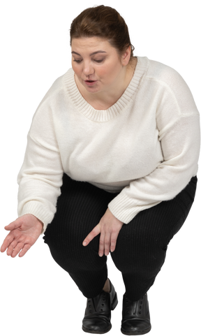 Vista frontale di una donna grassoccia in abiti casual accovacciata