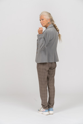 Rear view of an angry old woman in suit showing fist
