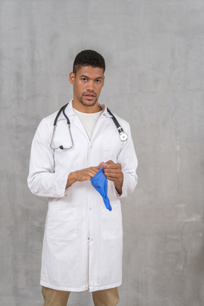 Male doctor putting on medical gloves