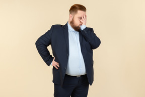 Sick and tired young overweight man closing face with a hand