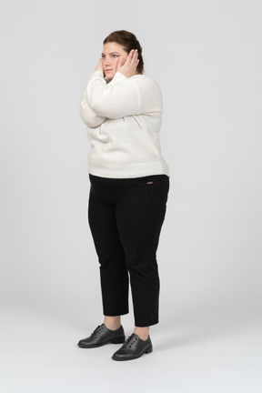 Vista lateral de uma mulher gorda em roupas casuais fechando as orelhas