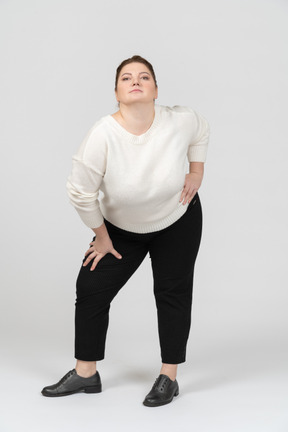 Mulher gorda em suéter branco em pé com as mãos nos quadris