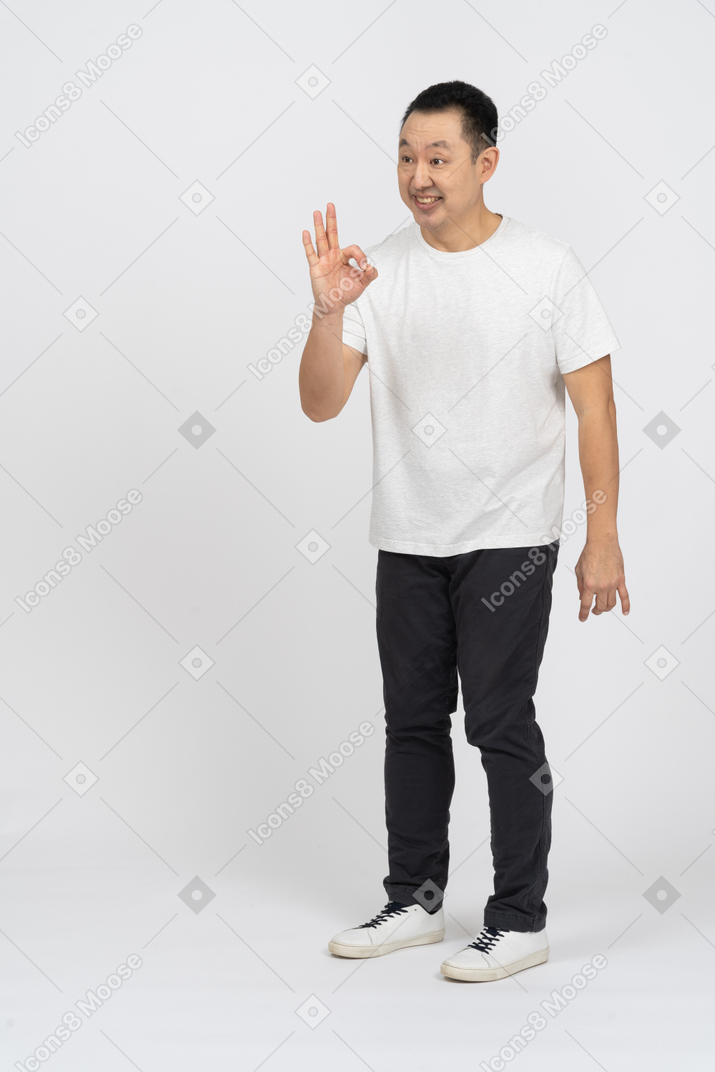 Vista frontal de um homem feliz em roupas casuais, mostrando sinal de ok