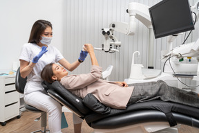 Full-length of a female dentist and her female patient looking at teeth model