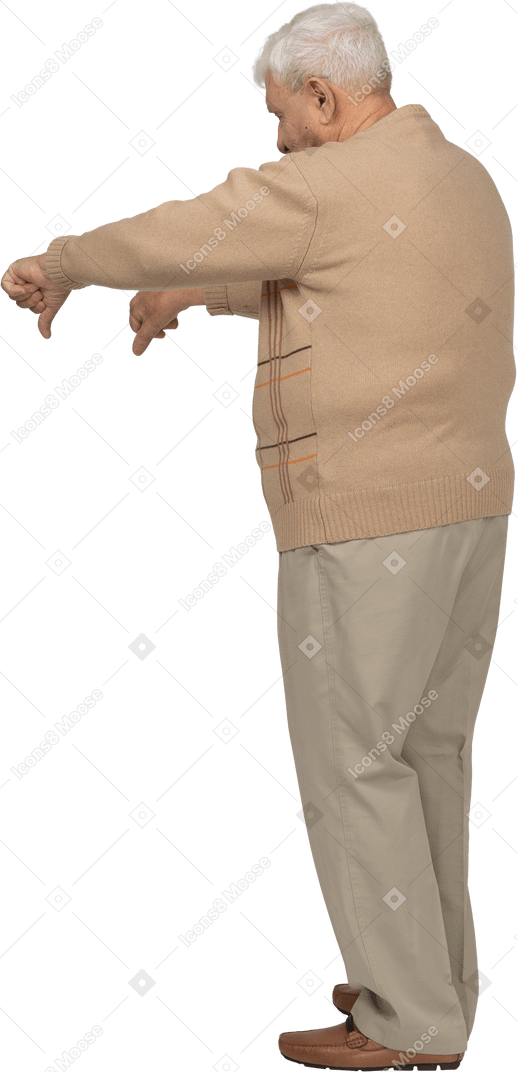 Vista lateral de un anciano con ropa informal que muestra los pulgares hacia abajo