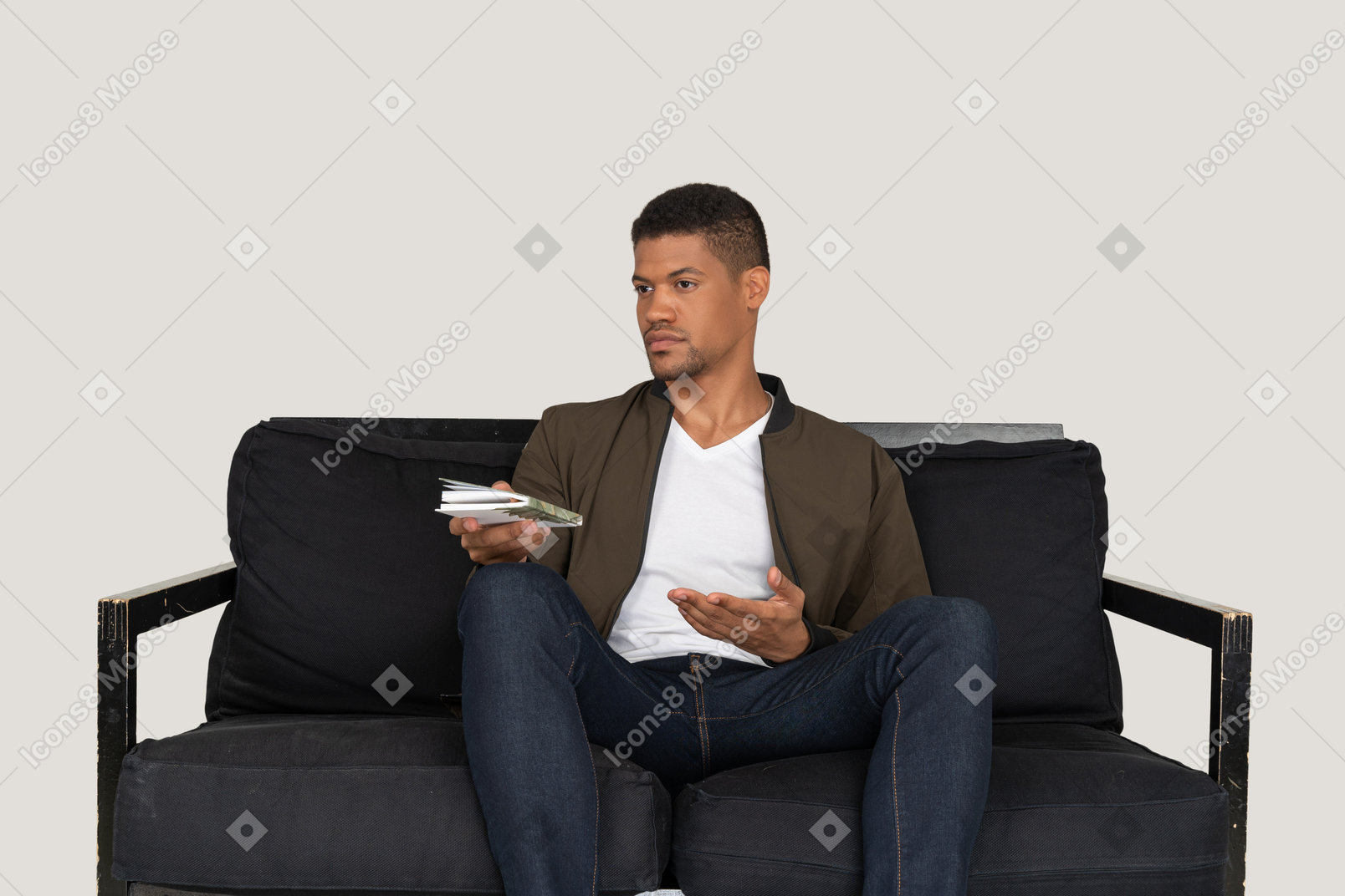 Front view of young man sitting on a sofa and passing pensil with notebook