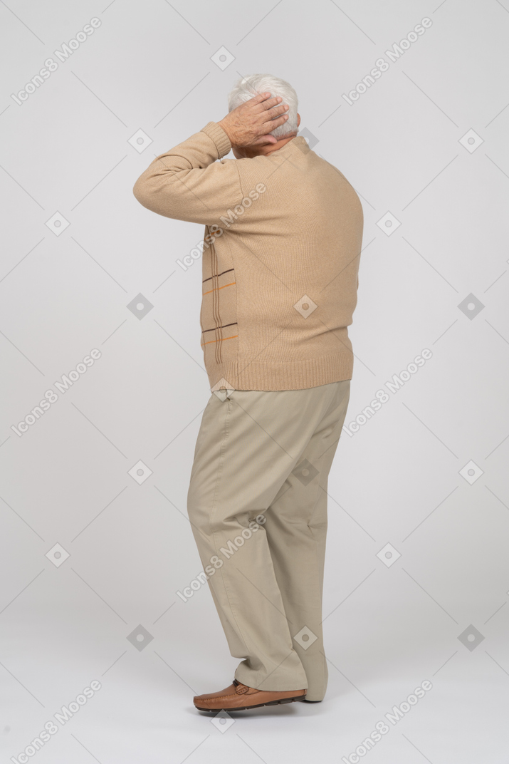 Side view of an old man in casual clothes posing with hand on head