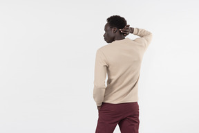 A young black man in a grey sweater standing alone on the white background