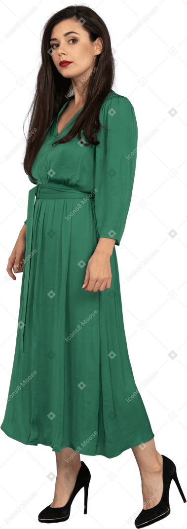Three-quarter view of a young lady in green dress looking at camera