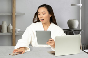 A woman sitting at a table using a tablet