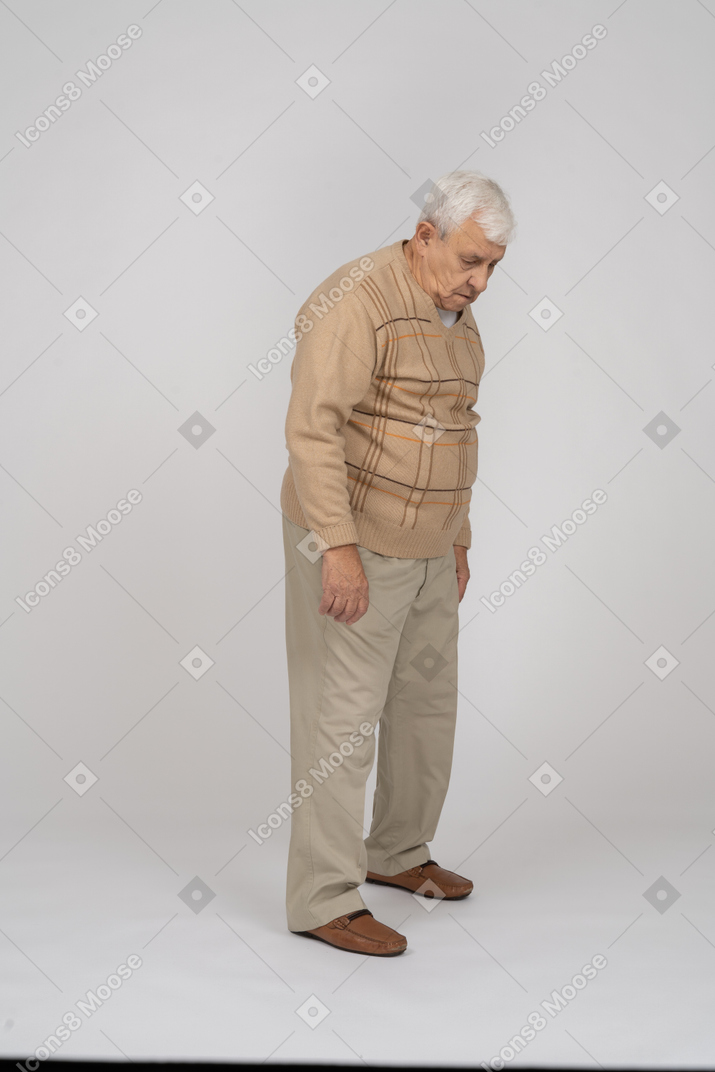 Vista lateral de un anciano triste con ropa informal mirando hacia abajo