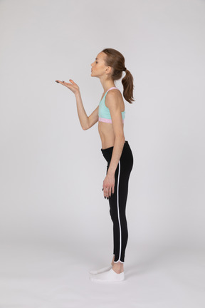 Side view of a teen girl in sportswear raising hand and arguing