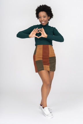 Cheerful afro girl making a heart gesture with her fingers