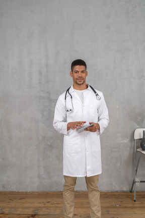 Front view of a male doctor holding a tablet