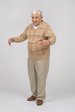 Front view of a happy old man in casual clothes standing with outstretched arms