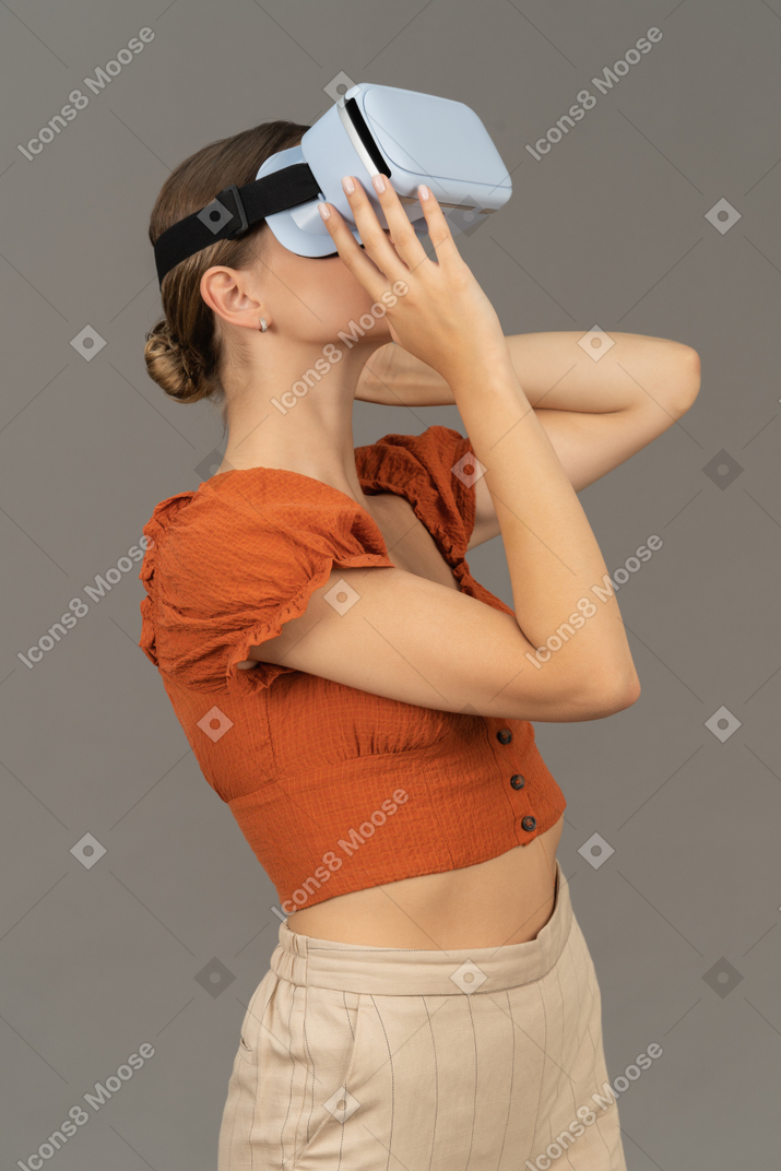 Vue de trois quarts d'une jeune femme prenant un casque vr