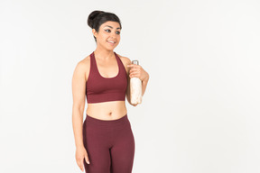 Jeune femme indienne sportswear tenant une bouteille de sport