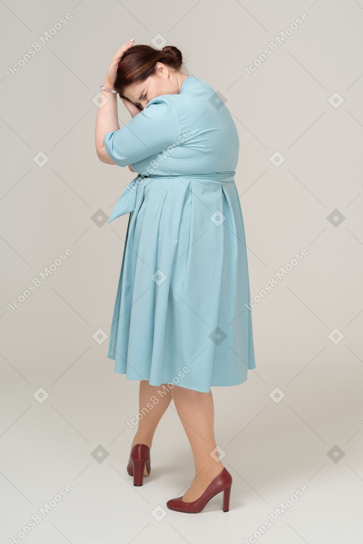 Vista laterale di una donna in abito blu che tocca la testa