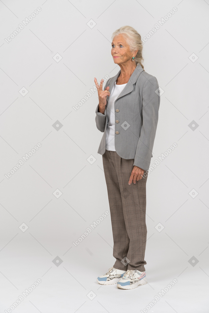 Vista lateral de una anciana haciendo el signo v con los dedos