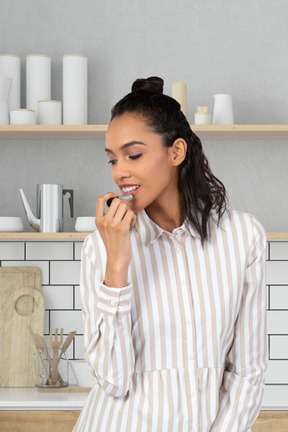 Woman applying lipstick in the kitchen