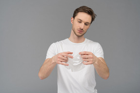 Front view of a young man unfolding facial mask