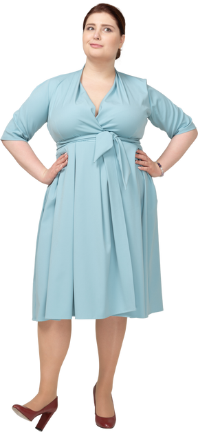 Vue de face d'une femme en robe bleue posant avec les mains sur les hanches