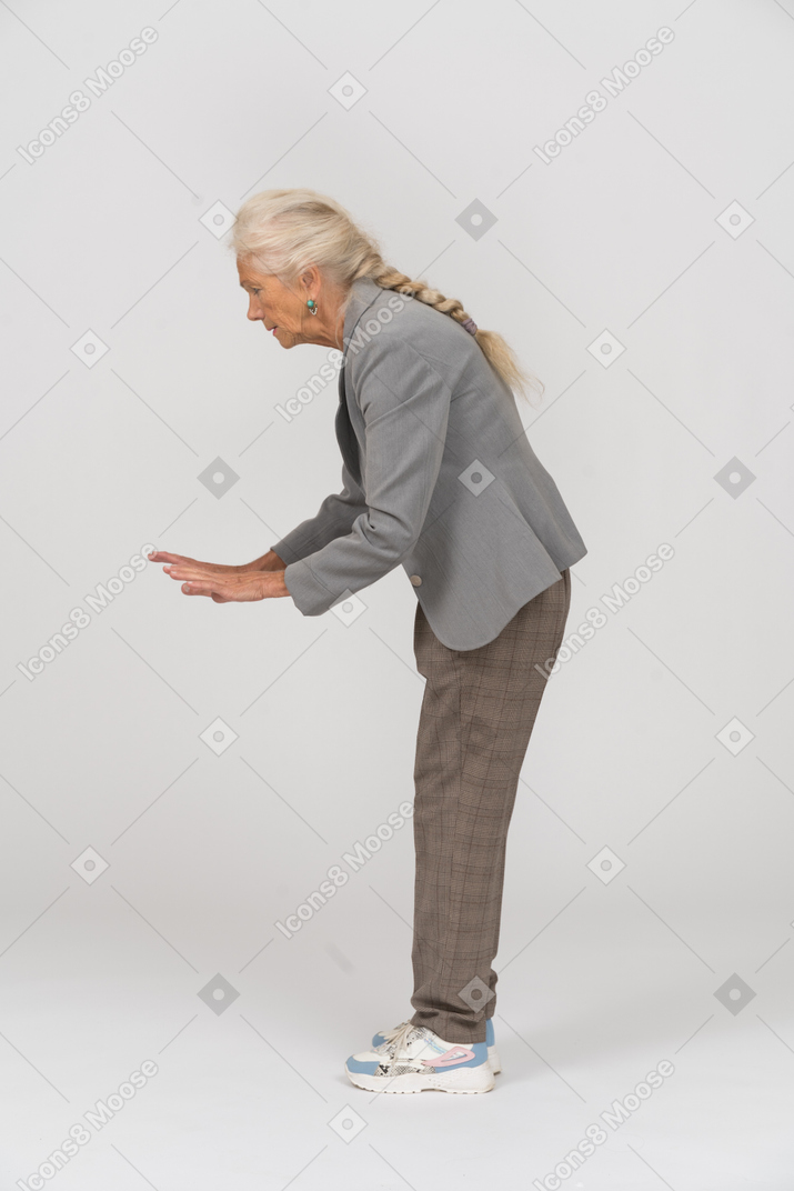 腰をかがめて一時停止の標識を示している老婦人の側面図