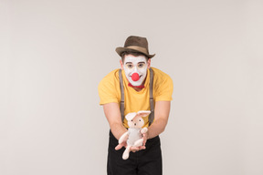 Male clown showing toy rabbit he's holding