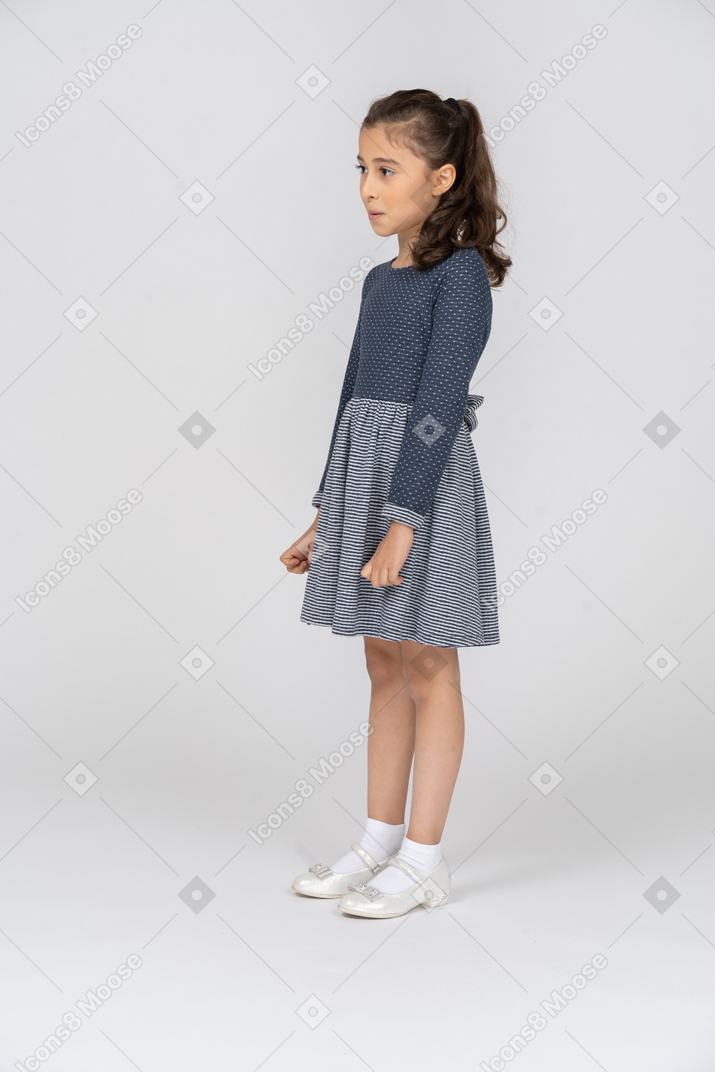 Vista de tres cuartos de una niña de pie y mirando sobresaltada