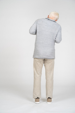 一个男人站在肘部弯曲双臂的后视图