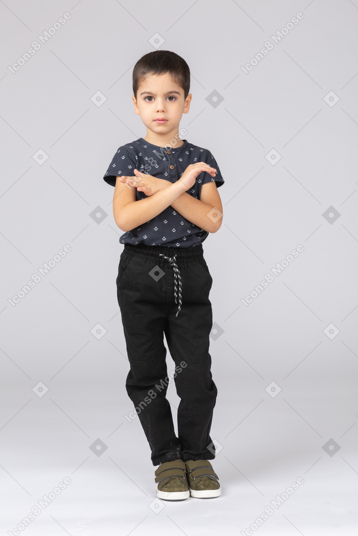 Cute boy in casual clothes looking at camera and showing stop gesture