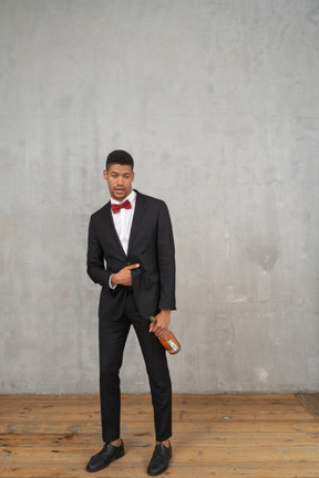 Front view of a drunk young man holding a champagne bottle