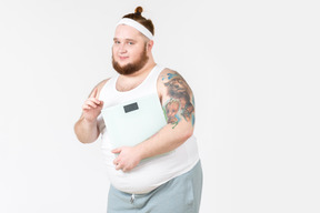 Большой парень в спортивной одежде держит цифровые веса
