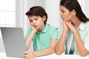 A woman and a boy are looking at a tablet