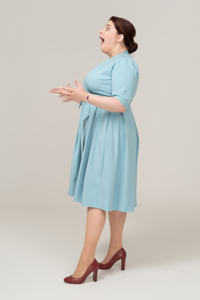 Mulher impressionada em vestido azul posando de perfil
