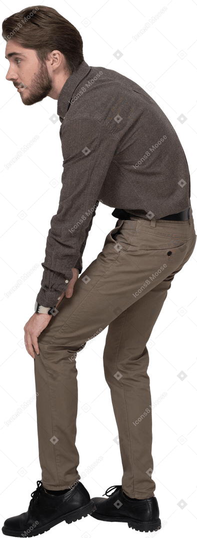 Vue latérale d'un jeune homme en vêtements de bureau touchant le genou