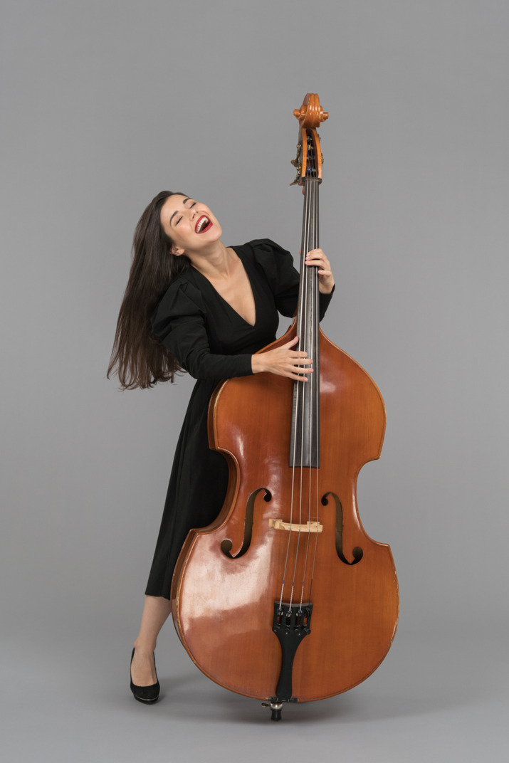 A cheerful young woman playing a double-bass