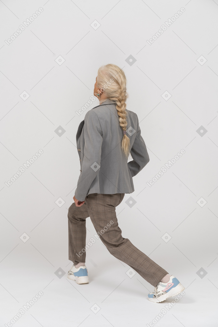 Rear view of an old lady in suit doing yoga
