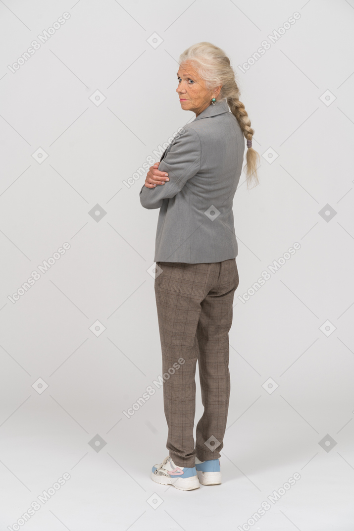 Vista posteriore di una vecchia signora in abito in posa con le braccia incrociate