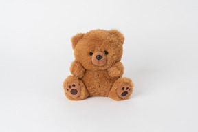 Un pequeño oso de peluche marrón lindo sentado aislado contra un fondo blanco liso