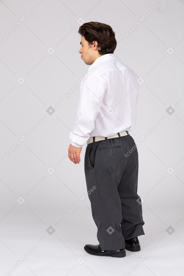 Vista posteriore di tre quarti di un giovane uomo in abiti casual da lavoro in piedi con gli occhi chiusi